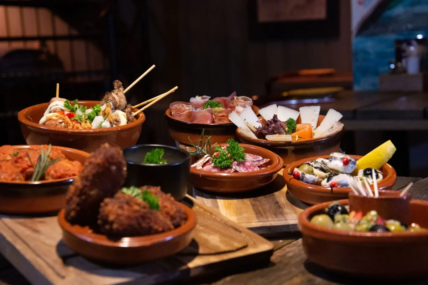 Fotografía real de una mesa con tapas variadas, imagen de ambientación